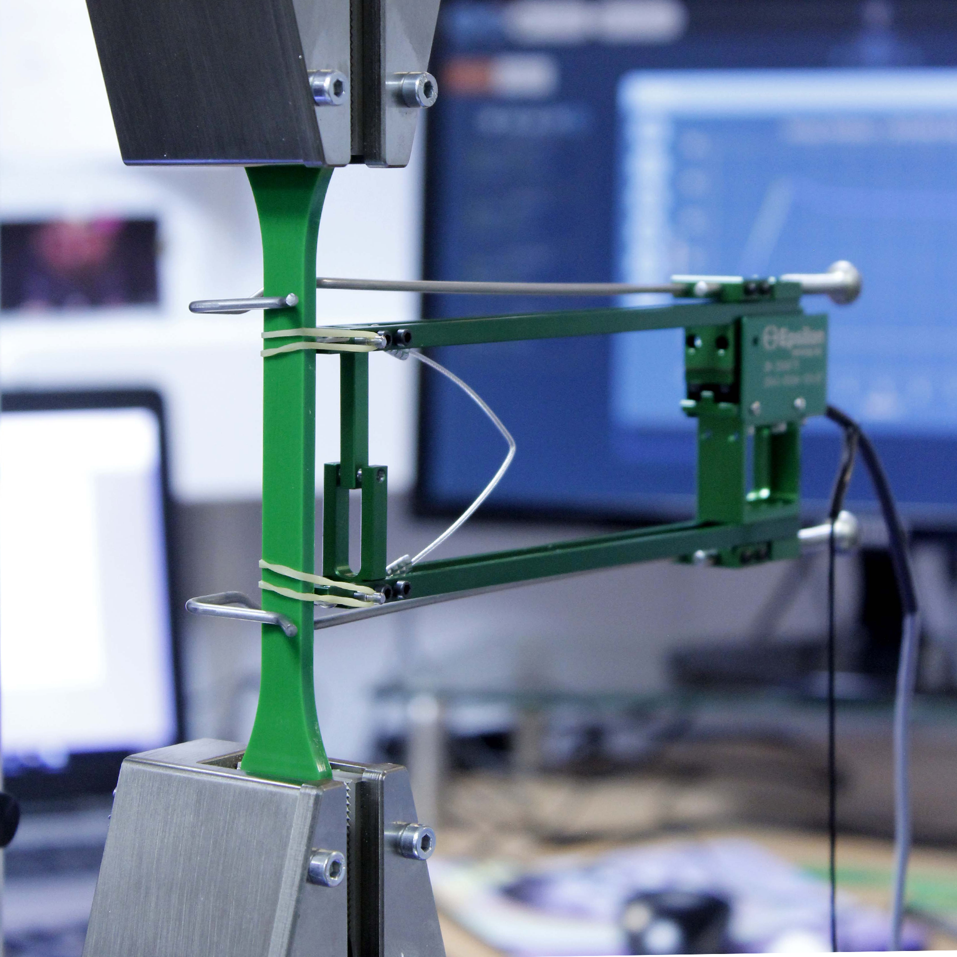 Close up photo of a contact extensometer on a materials specimen during tensile strength testing on a Universal Tester
