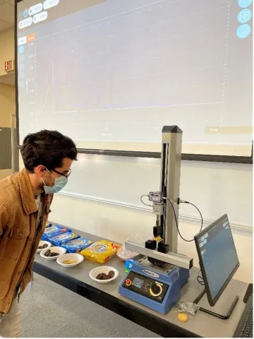 Student observes a three-point bend test of an Oreo, part of an in-class laboratory in their Introduction to Materials Science course. Real-time results from the MultiTest are projected in the classroom.